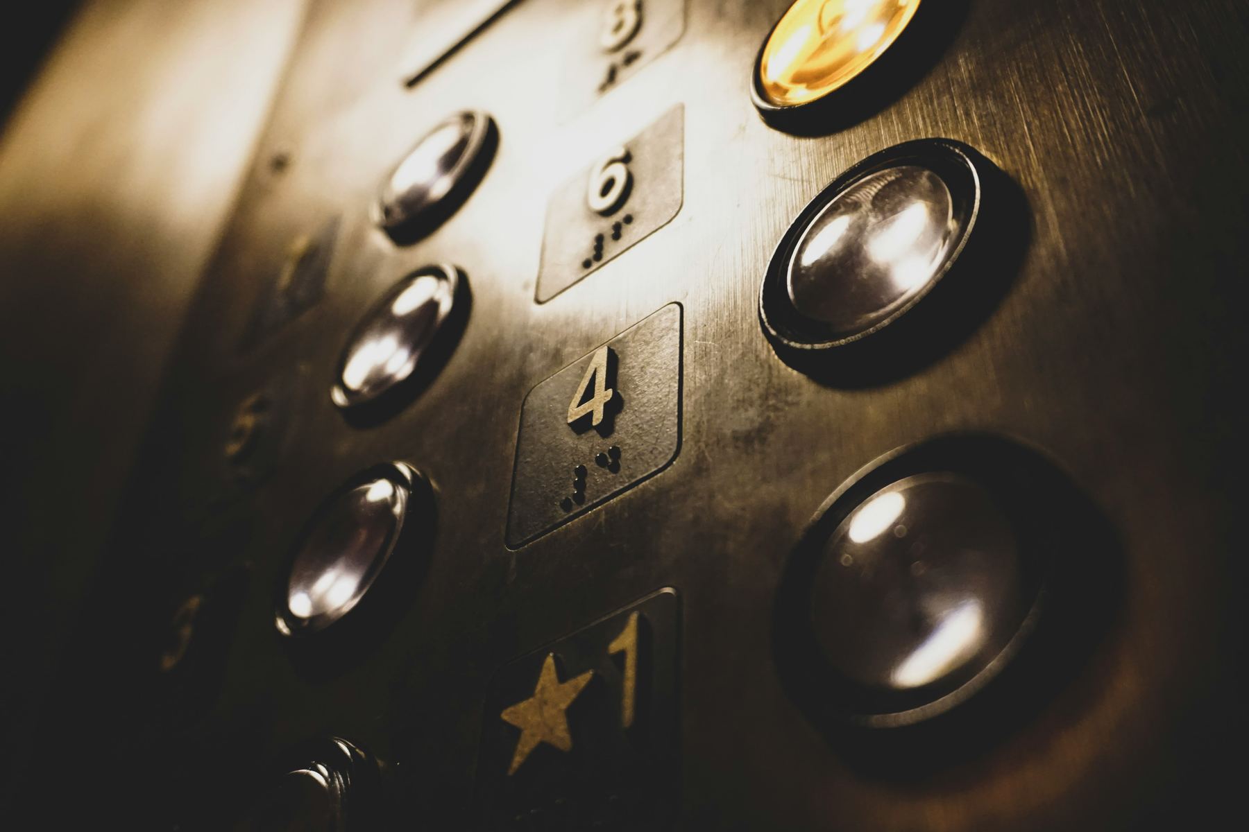 Close-up macro shot of worn brass elevator control panel buttons