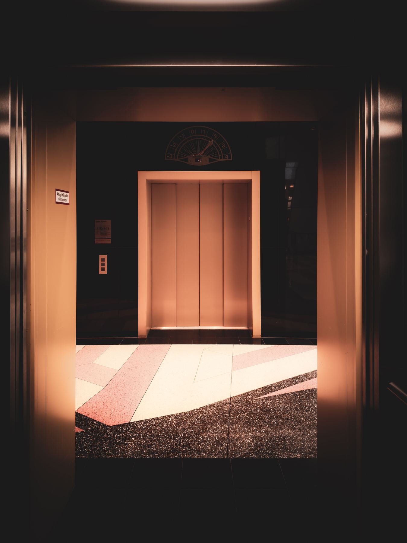 Warm, softly lit hotel-style corridor leading to an open elevator