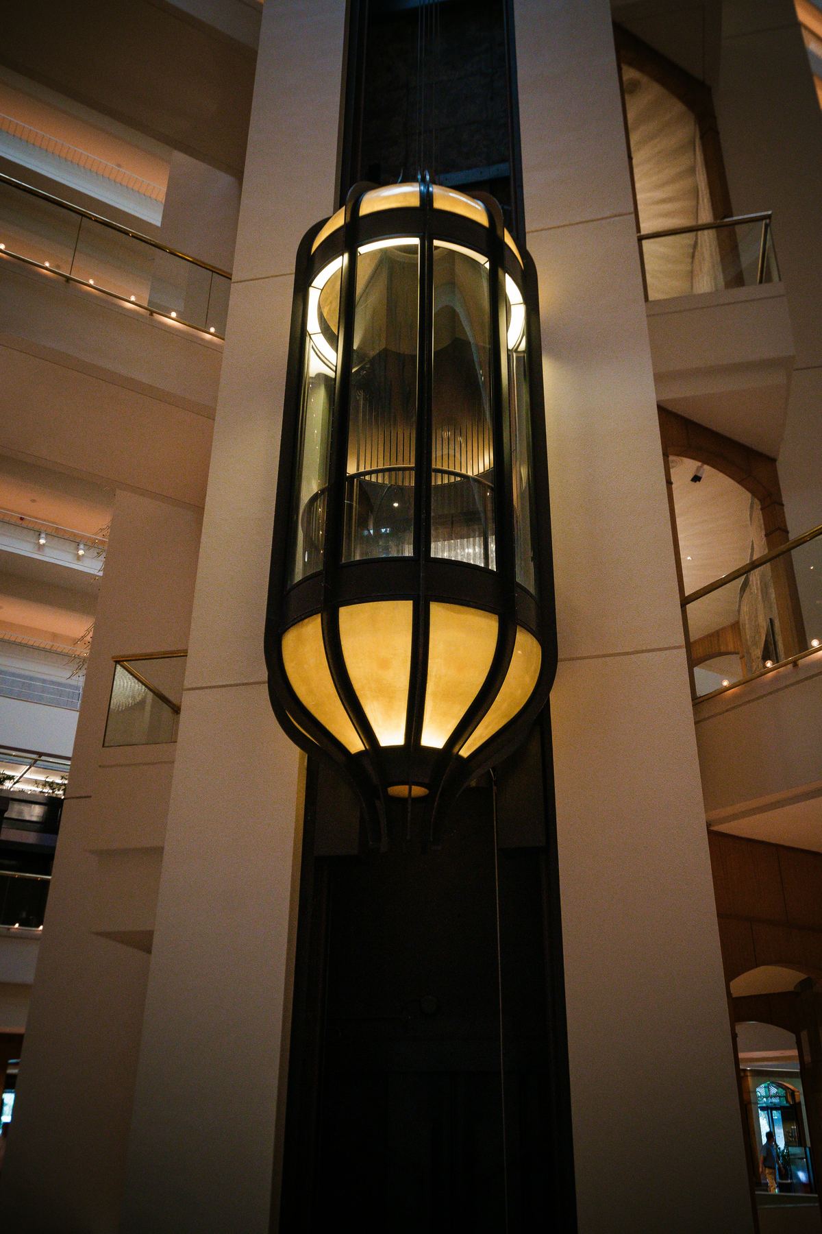 Warmly lit glass observation elevator inside a building atrium