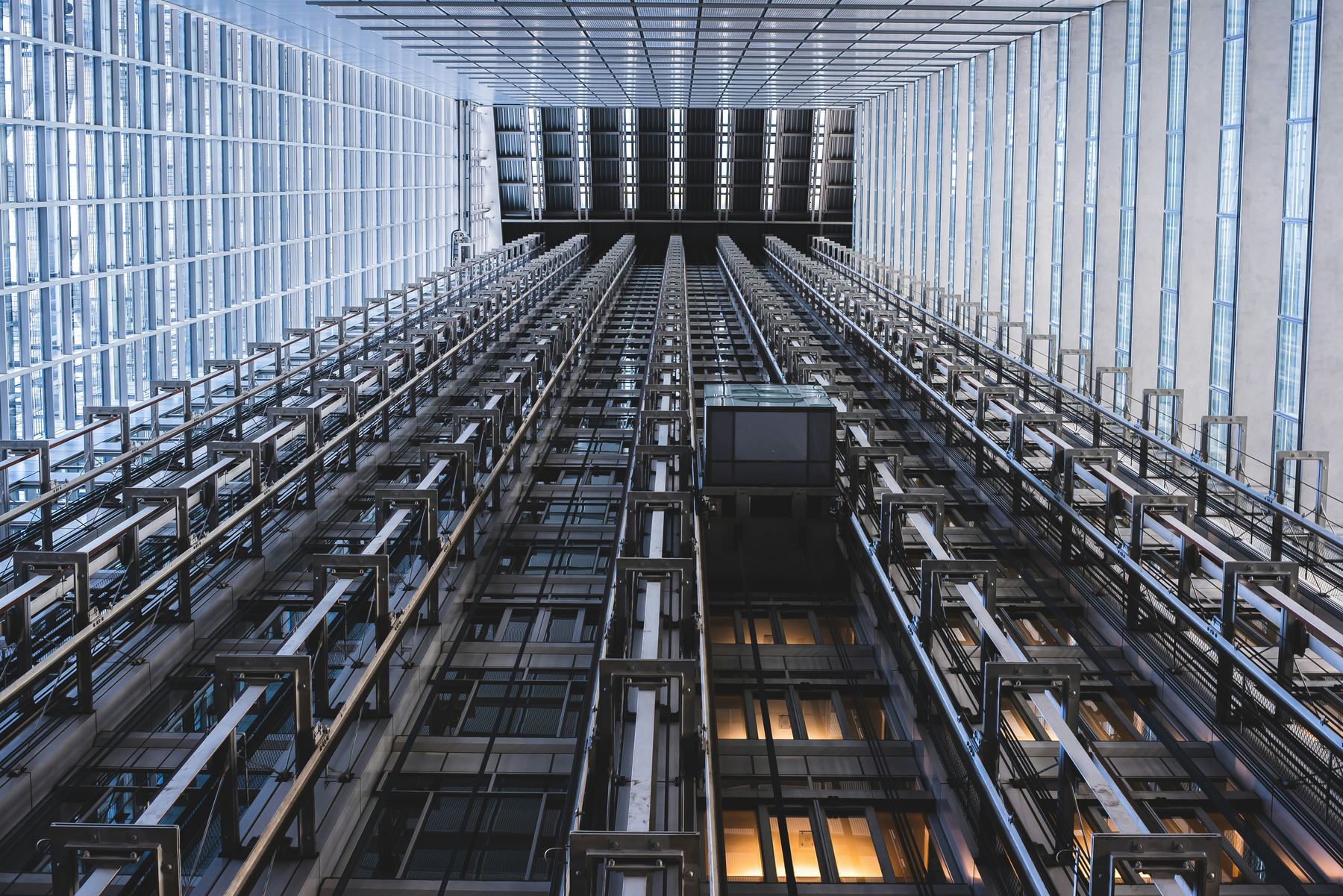 Symmetrical view looking up an elevator shaft showing the mechanism and guide rails