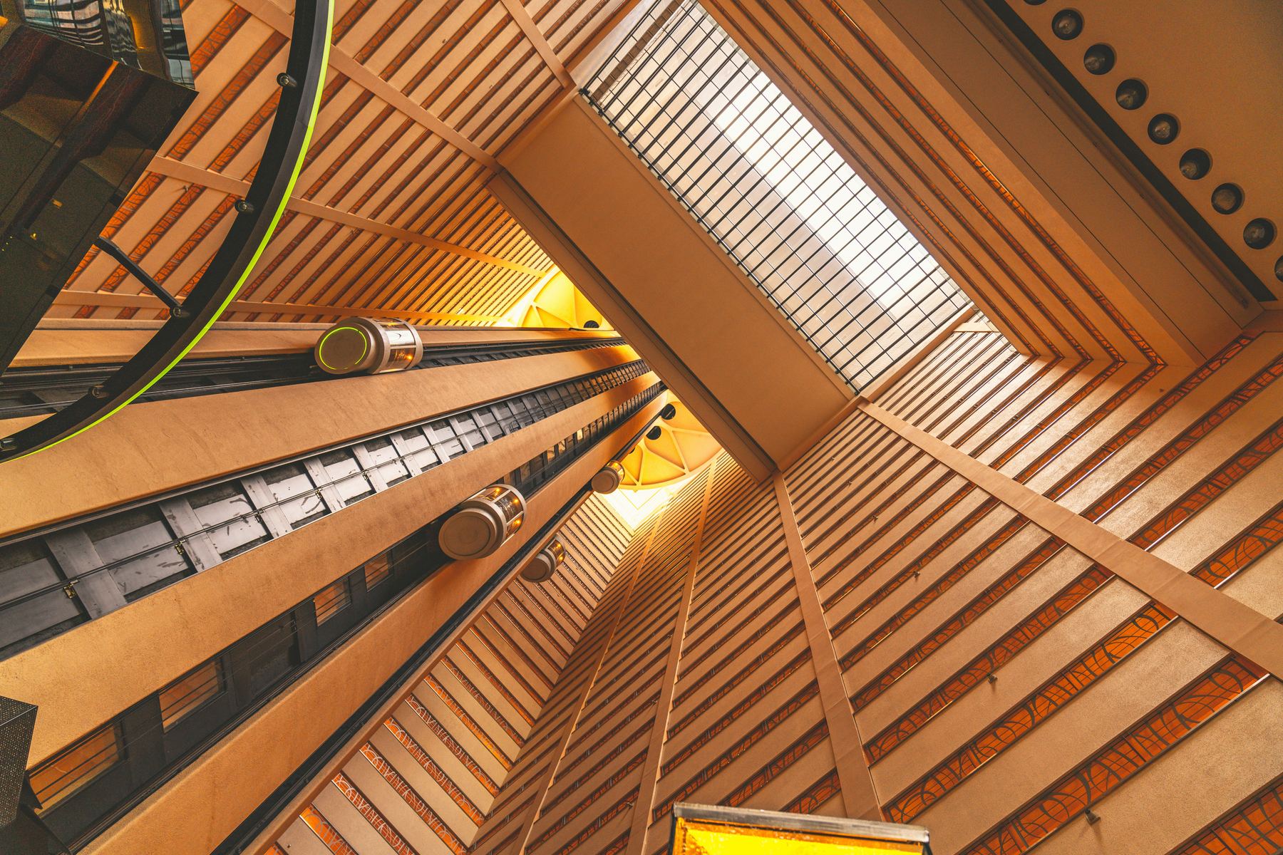 View looking up an elevator shaft in a warm wood-paneled architectural atrium