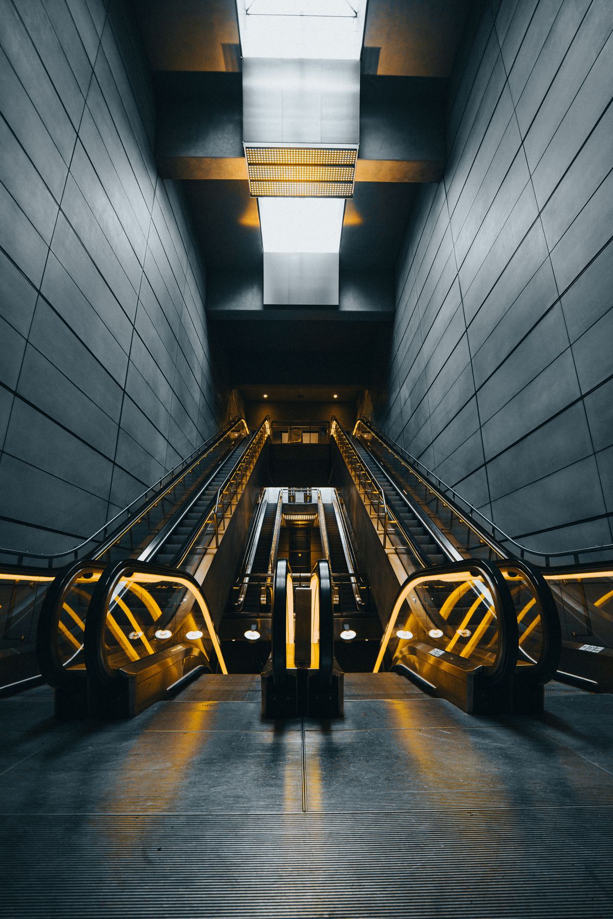 Escalator descending into an underground station with warm gold and teal lighting