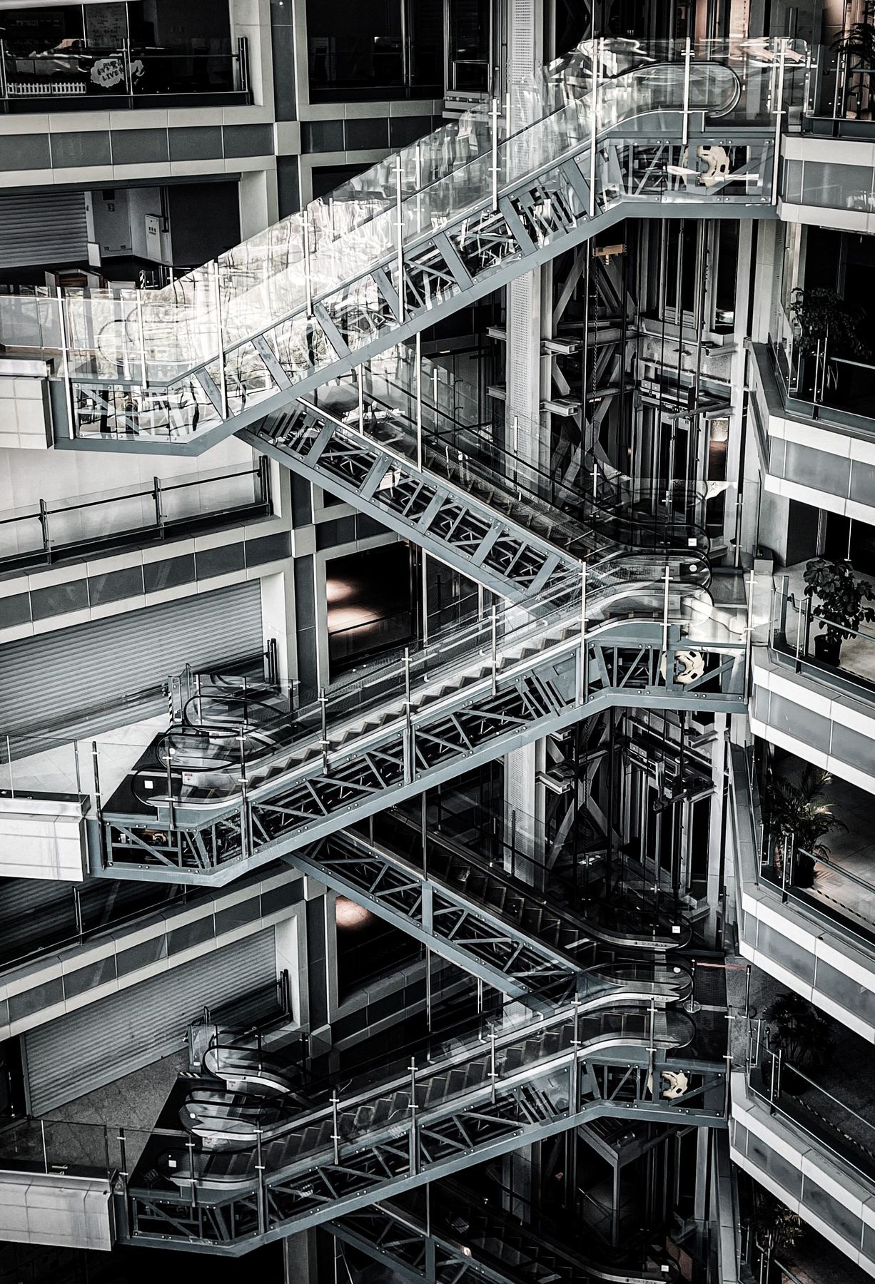 Dramatic zigzagging glass escalators inside a modern commercial atrium